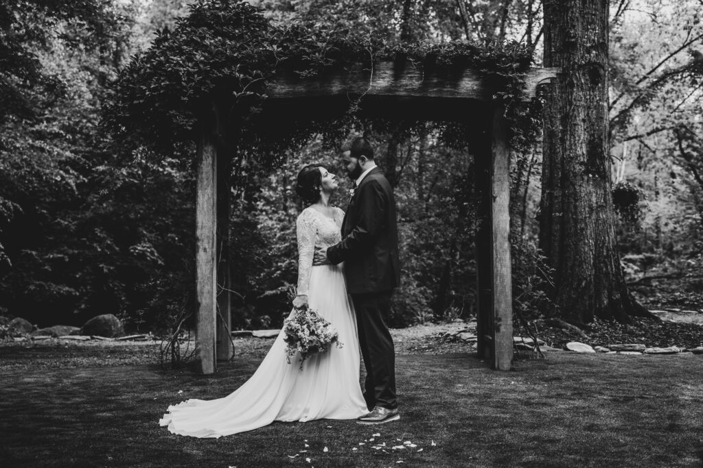 A stunning wedding moment captured at the Historic Robertson Homestead in Rock Hill, SC, designed and coordinated by Crafted Charm Wedding Planning. The romantic setting, surrounded by lush greenery and Southern charm, showcases the couple's love and the expert floral arrangements by Crafted Charm.