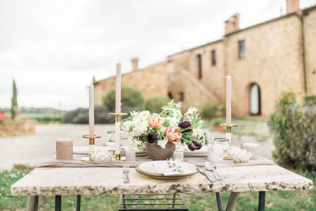 peach, pink, and plum florals at sweetheart table with villa estate in backdrop and sweetheart table is granite with modern candle holders and dining pieces
