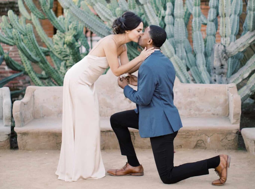 Bride and Groom proposal engagement with groom on one knee and bride kissing groom