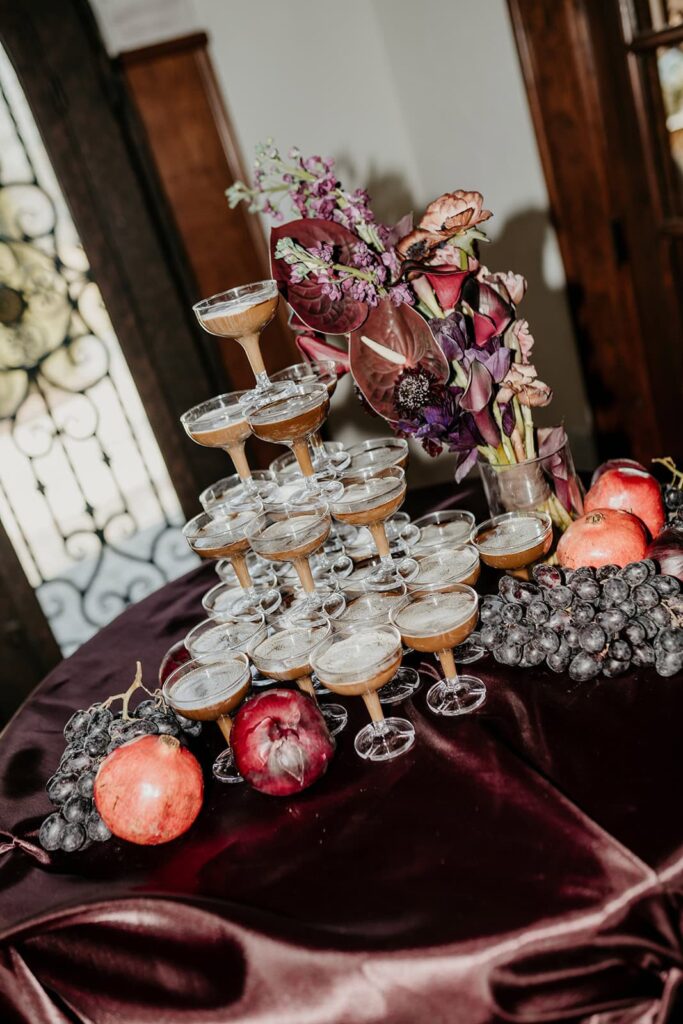 Sunset Ridge Estate luxury southern wedding venue in Monroe NC with moody winter espresso tower in front of entry at large estate with gold candles and large florals and fruit in shades of chocolate brown and burgundy by Crafted Charm Florals