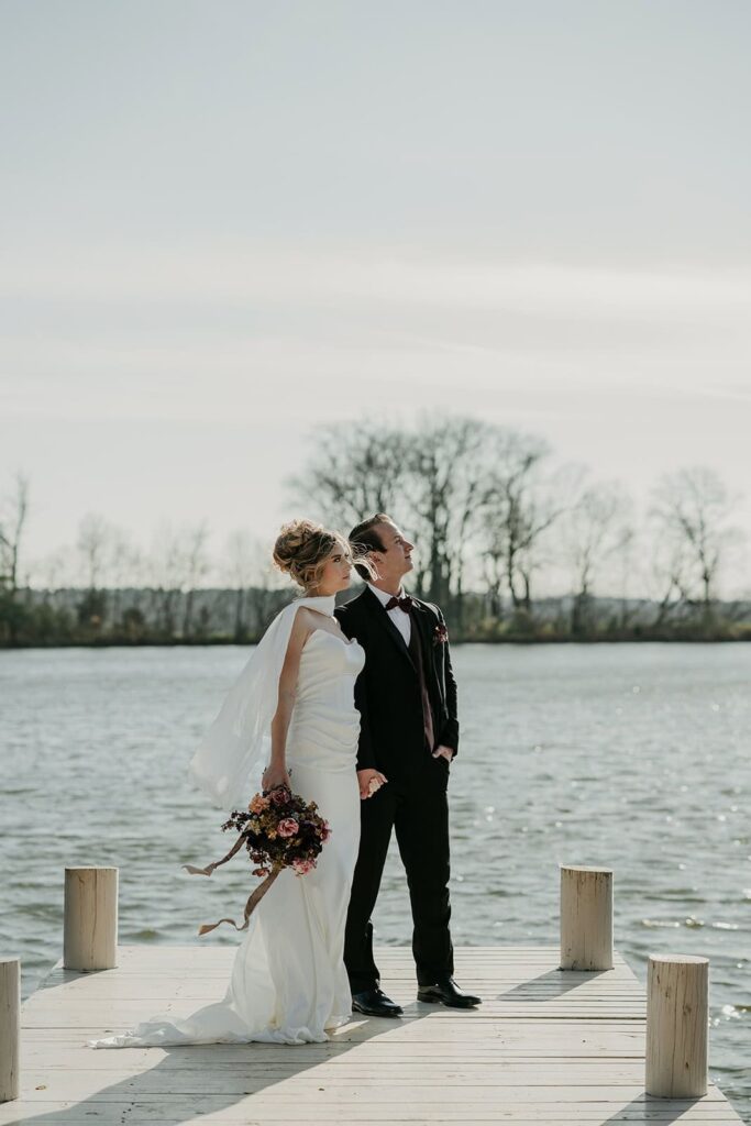 Sunset Ridge Estate luxury southern wedding venue in Monroe NC with bride and groom walking outside of large estate at lakeside property at lake dock for newlywed portraits