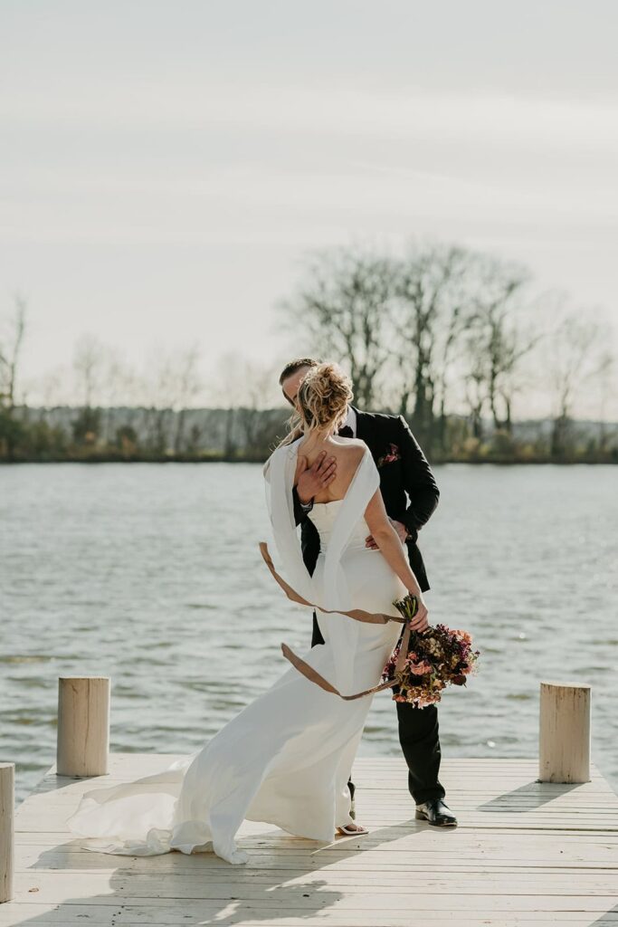 Sunset Ridge Estate luxury southern wedding venue in Monroe NC with bride and groom walking outside of large estate at lakeside property at lake dock for newlywed portraits