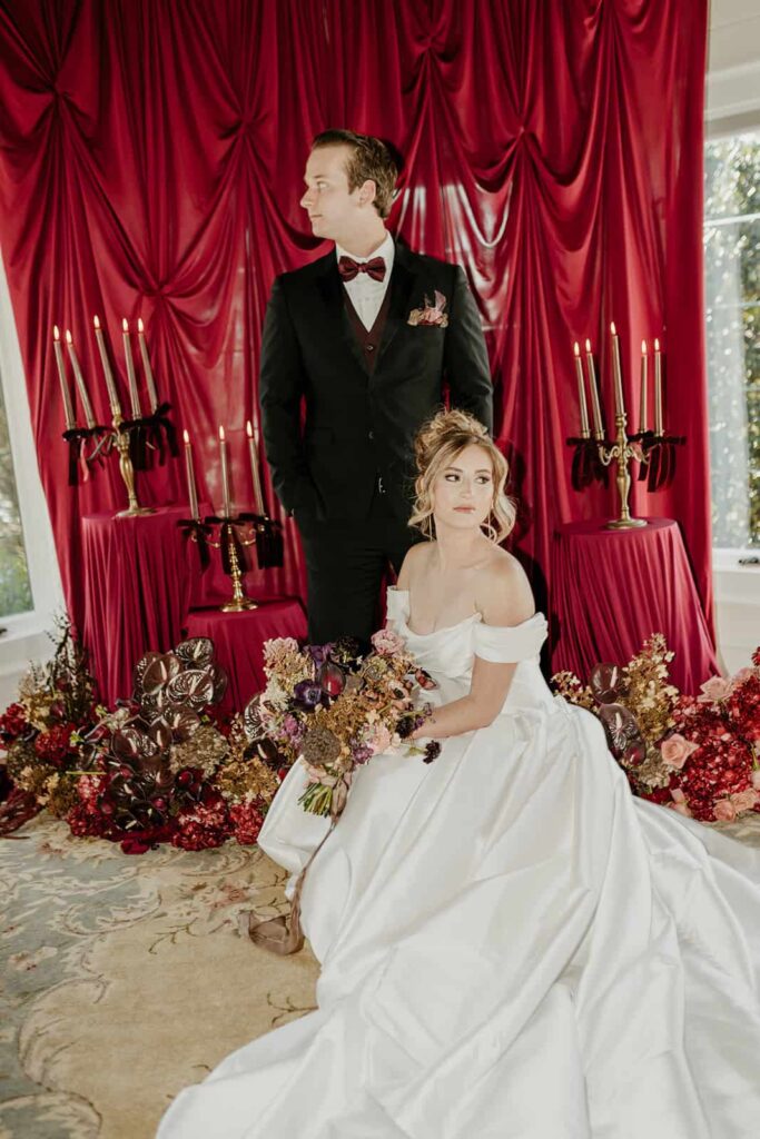 Sunset Ridge Estate luxury southern wedding venue in Monroe NC with bride and groom portraits moody winter luxury draping backdrop with candels and large floral installations at large estate for newlywed portraits
