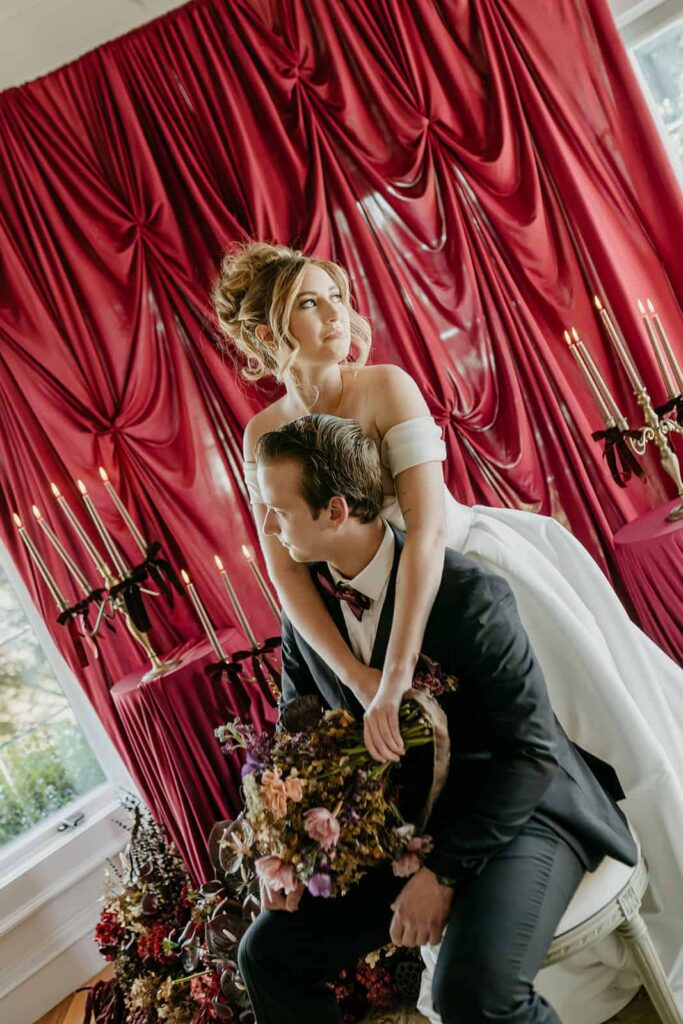 Sunset Ridge Estate luxury southern wedding venue in Monroe NC with bride and groom portraits moody winter luxury draping backdrop with candels and large floral installations at large estate for newlywed portraits