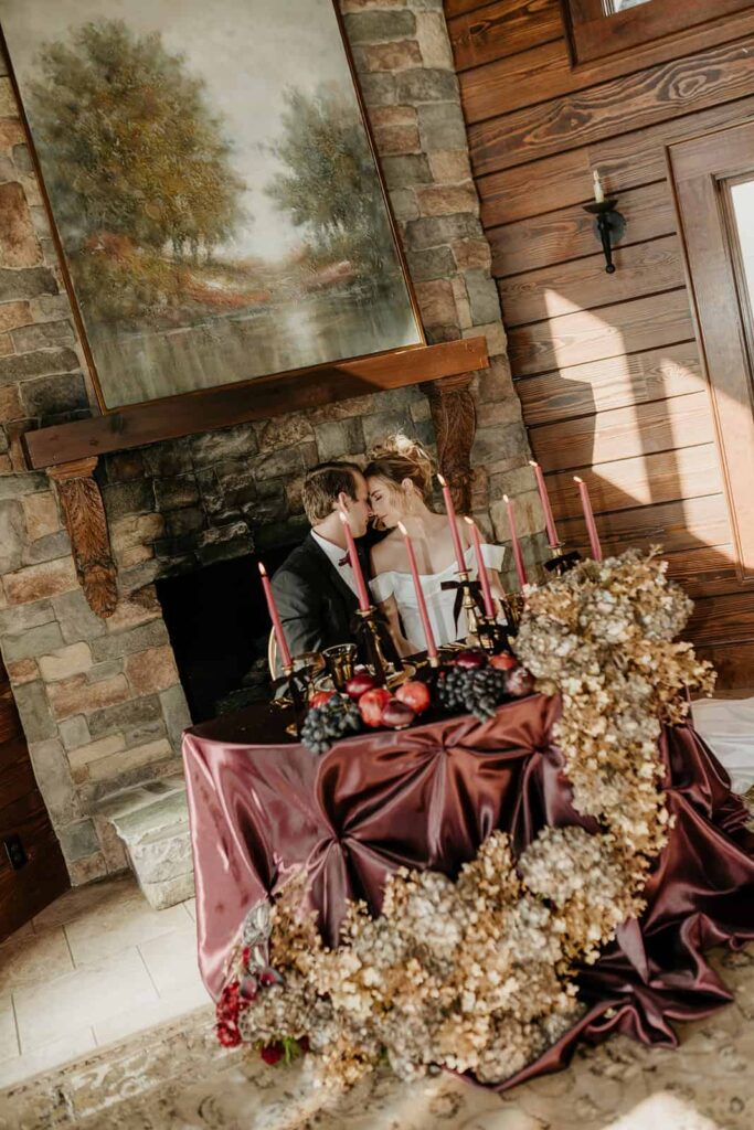 Sunset Ridge Estate luxury southern wedding venue in Monroe NC with bride and groom toasting at moody winter sweetheart table in front of fireplace at large estate for newlywed portraits