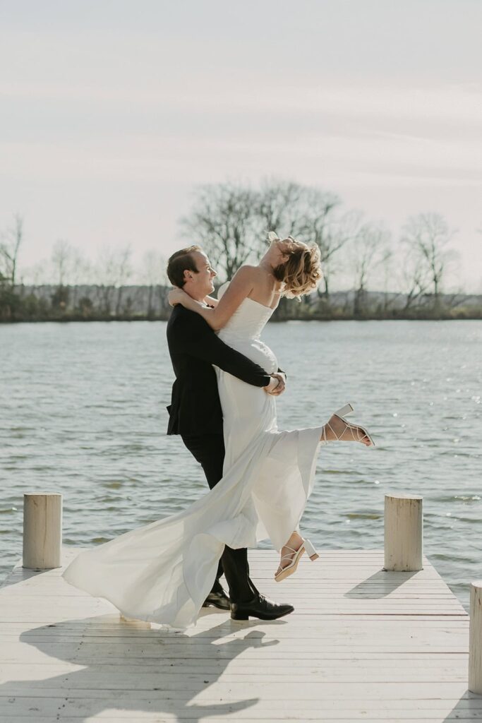 Sunset Ridge Estate luxury southern wedding venue in Monroe NC with bride and groom walking outside of large estate at lakeside property at lake dock for newlywed portraits