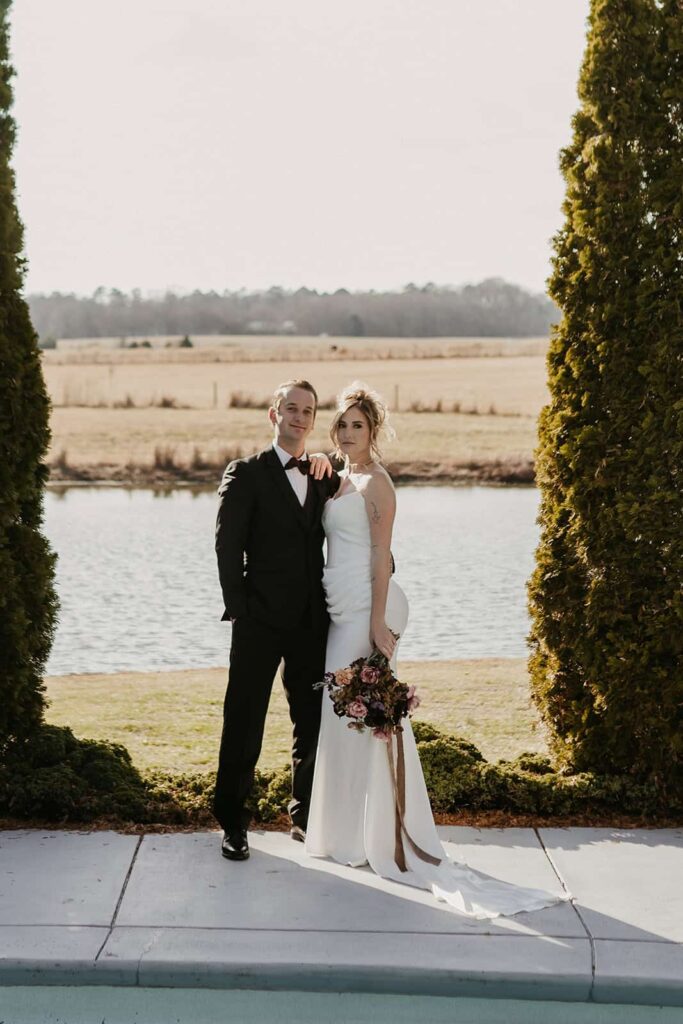 Sunset Ridge Estate luxury southern wedding venue in Monroe NC with bride and groom walking outside of large estate for newlywed portraits by pool