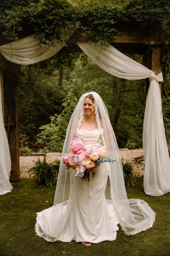 bride portrait carrying large floral bouquet of spring colors and peonies at the Historic Robertson Homestead in Rock Hill, SC