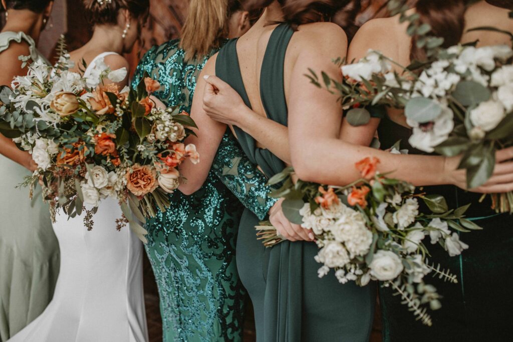 bride and bridesmaids holding each other holding autumn floral bouquets 