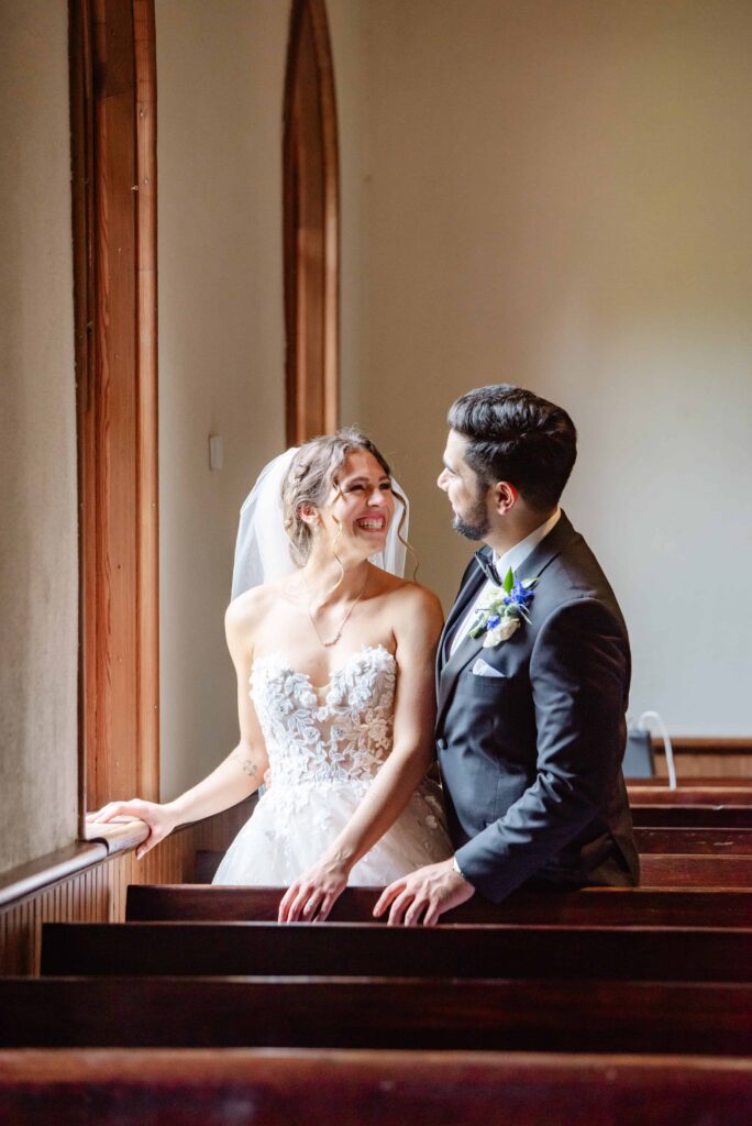 Bride and groom portrait in chapel at The Rafters at Historic St. Mark in Huntersville, NC at a classic blue and white styled wedding.