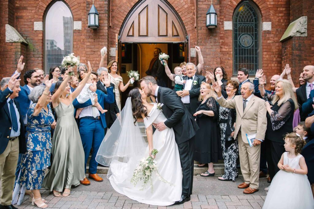 Receiving line for bride and groom, kissing, outside of St. Peters Catholic Church in Charlotte NC following a ceremony