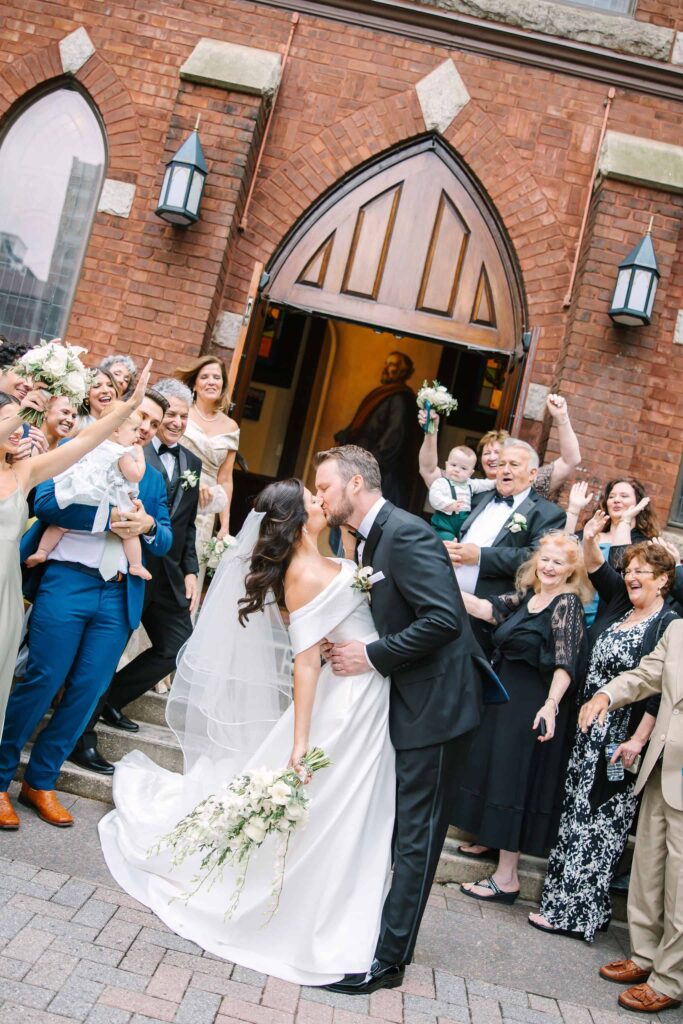 Receiving line for bride and groom, kissing, outside of St. Peters Catholic Church in Charlotte NC following a ceremony