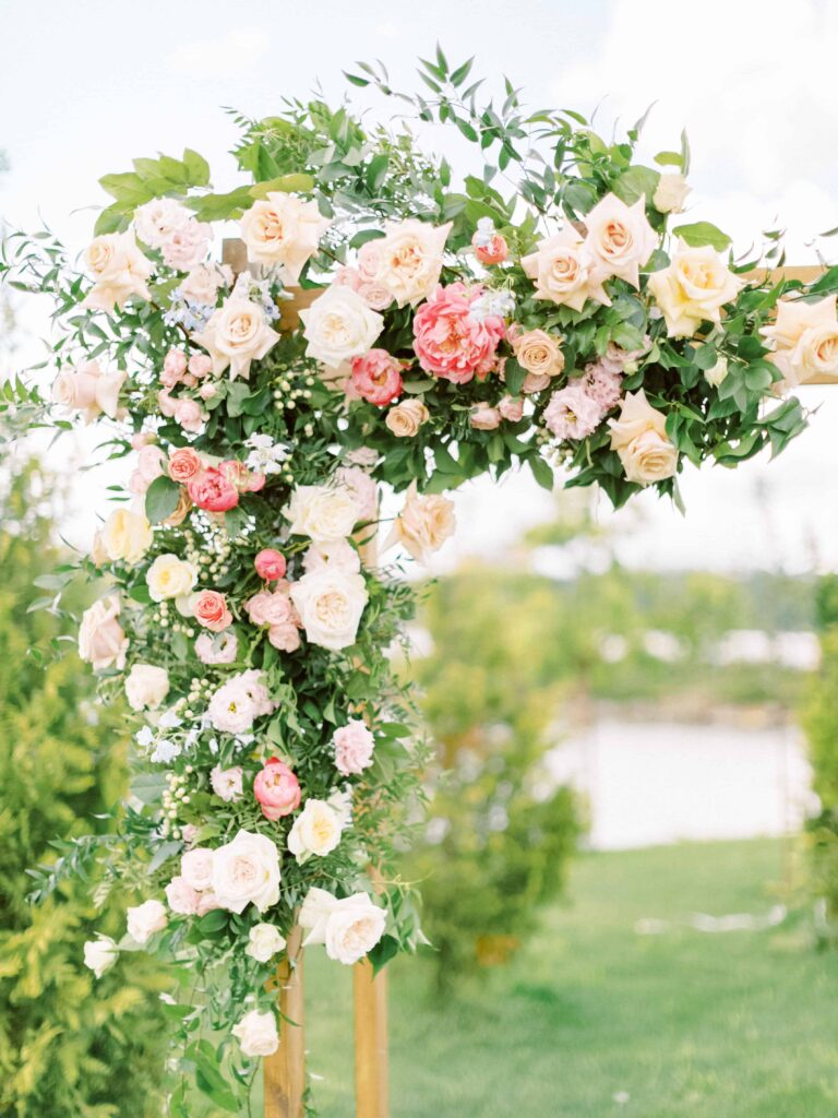 floral arch swag installation for a wedding ceremony in soft neutrals and pinks