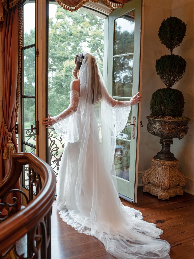 Le Chateau Du Coeur Wedding- bride in gown standing at Juliet balcony