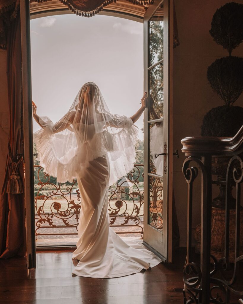 Le Chateau Du Coeur Wedding- bride in gown standing at Juliet balcony