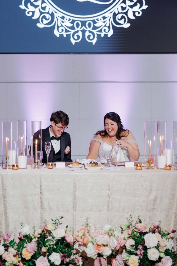 Bride and groom sweetheart table at The Revelry Charlotte NC wedding venue decorated in luxury florals with gold and soft pink accents by Crafted Charm Florals